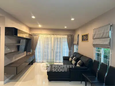 Spacious modern living room with sleek black leather sofa and stylish entertainment unit.