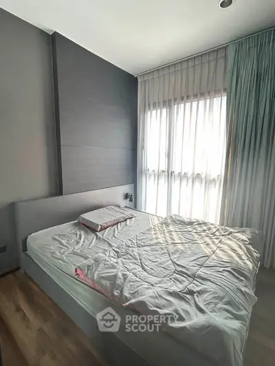 Cozy bedroom with natural light and modern decor, featuring a comfortable bed and elegant curtains.