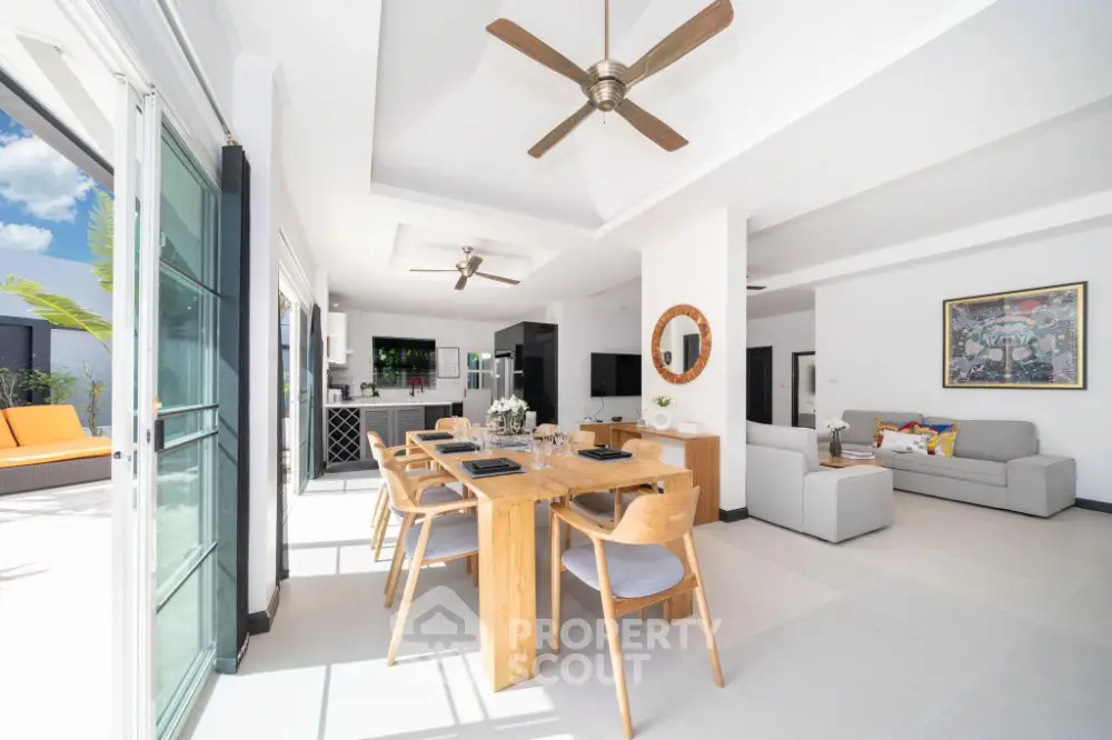 Spacious open-plan living area with high ceilings, modern furnishings, and seamless indoor-outdoor flow to a sunlit balcony, perfect for entertaining.