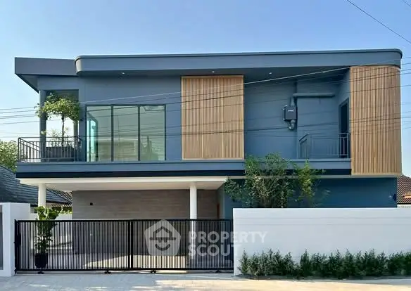 Modern two-story house with sleek design and large windows, featuring a stylish facade and gated entrance.