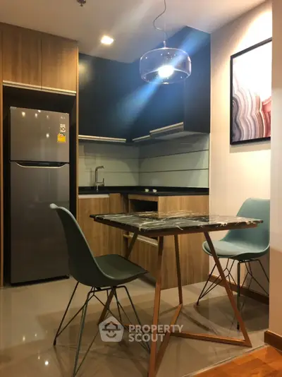 Modern kitchen with sleek appliances and stylish dining area in contemporary apartment.