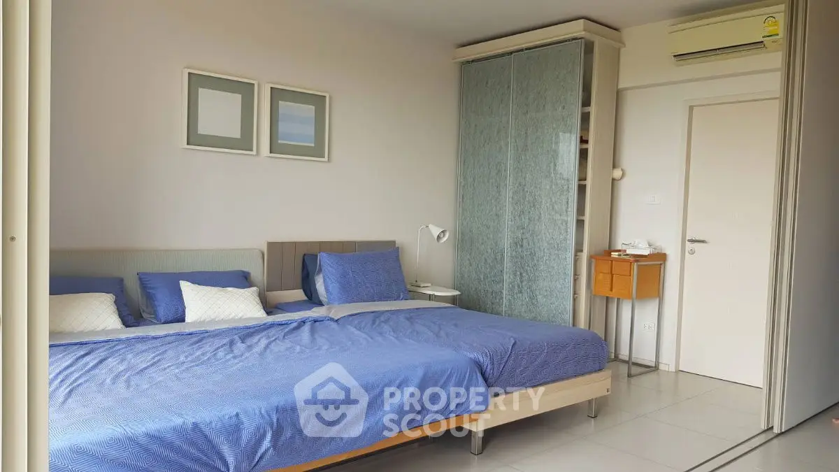 Spacious bedroom with modern decor and large bed, featuring stylish blue bedding and sleek storage solutions.