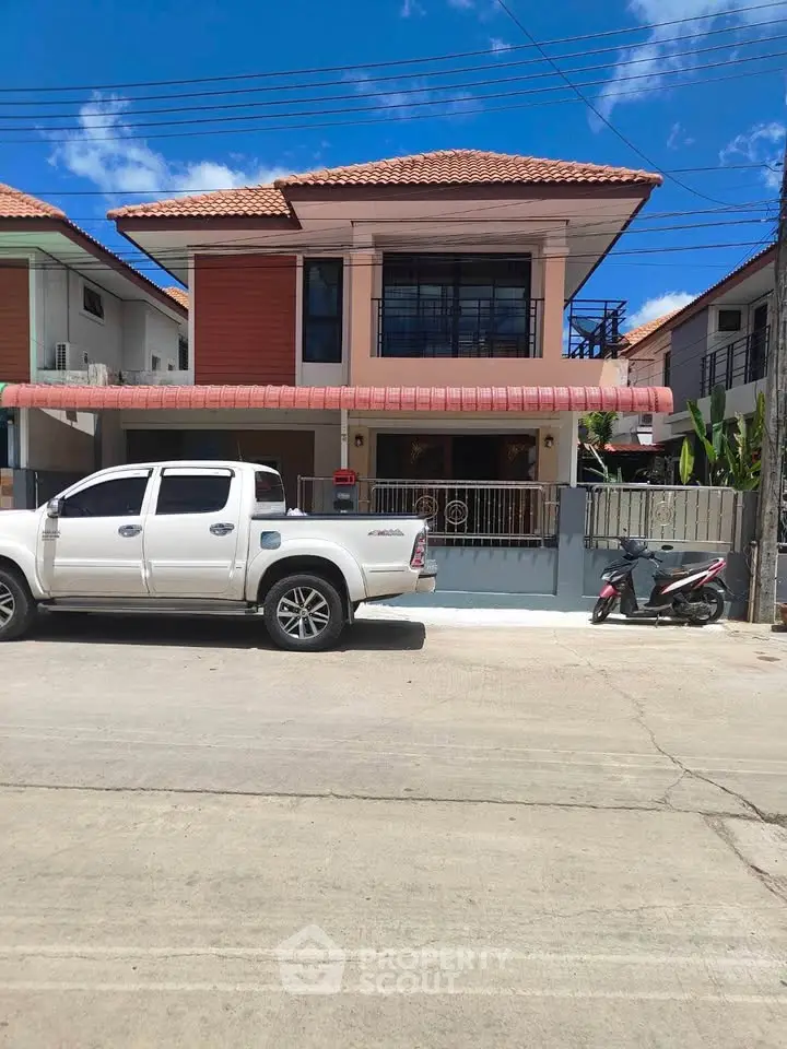 Charming two-story house with red roof and spacious driveway in a serene neighborhood.