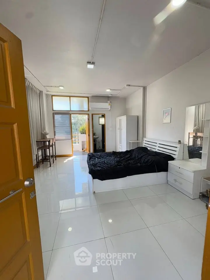 Spacious bedroom with modern decor and large windows offering natural light and outdoor access.