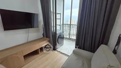 Modern living room with balcony and washing machine, featuring sleek TV and wooden cabinet.