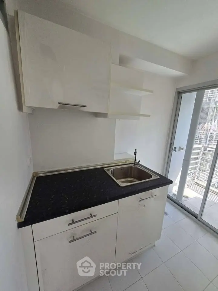 Modern kitchen with sleek cabinetry and balcony access in a bright apartment.