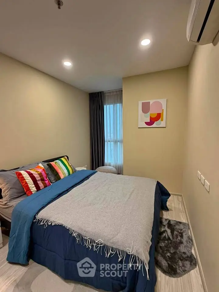 Cozy bedroom with modern decor and ample natural light, perfect for relaxation.