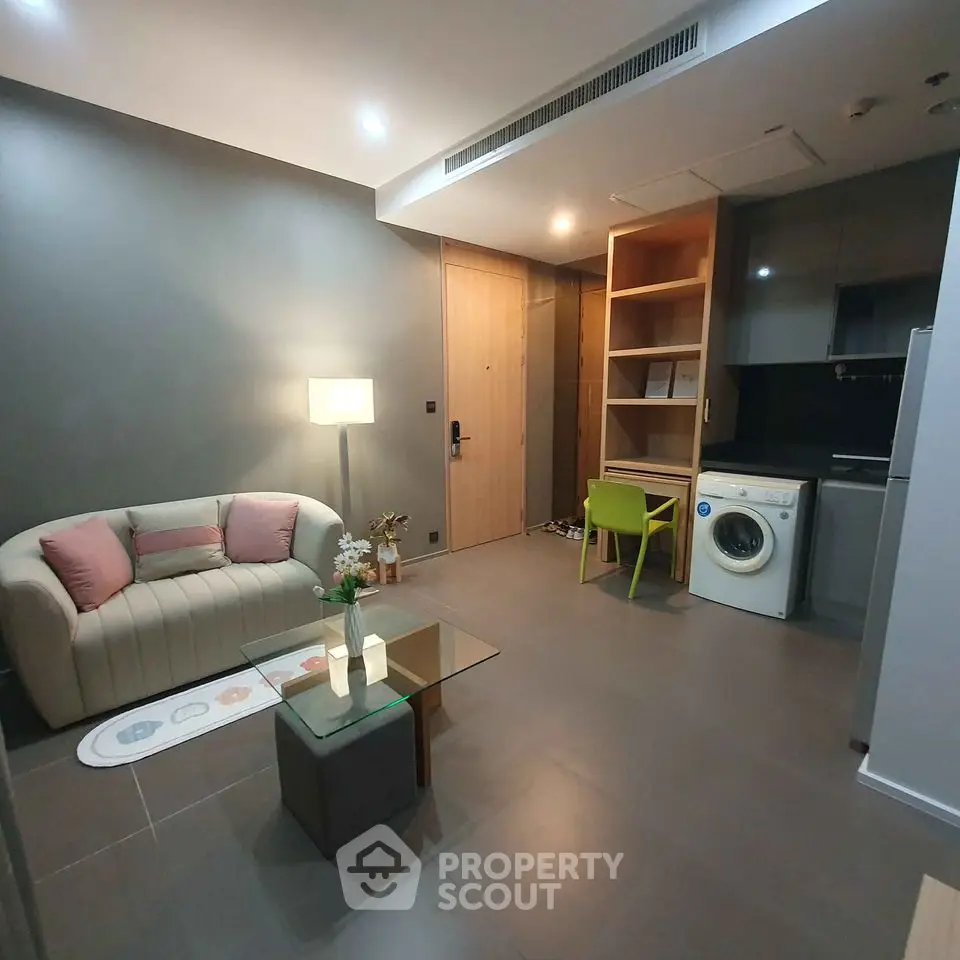 Modern living room with washing machine and stylish furniture in open layout apartment