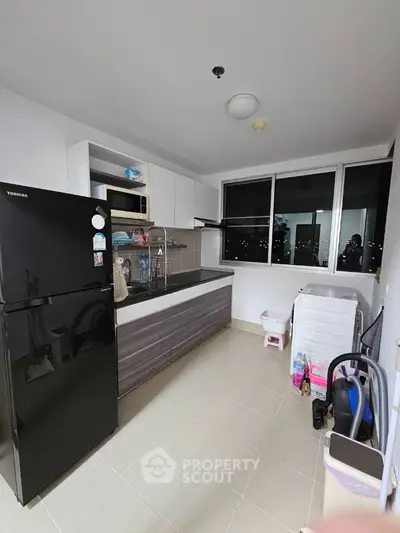 Modern kitchen with sleek black fridge and ample storage space