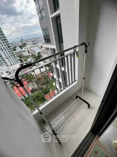 Compact balcony with city view, ideal for drying clothes, in a modern high-rise apartment.