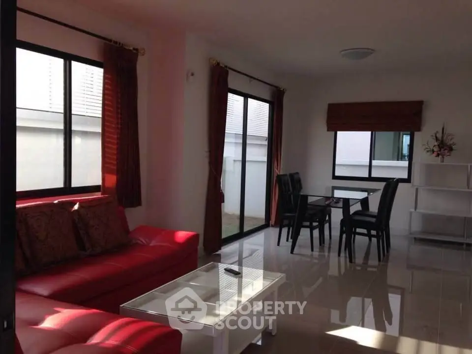 Spacious living room with red sofa and dining area in modern home