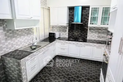 Modern kitchen with sleek black and white design, featuring gas stove and ample cabinetry.