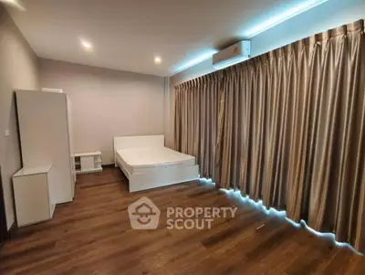 Spacious modern bedroom with elegant curtains and wooden flooring