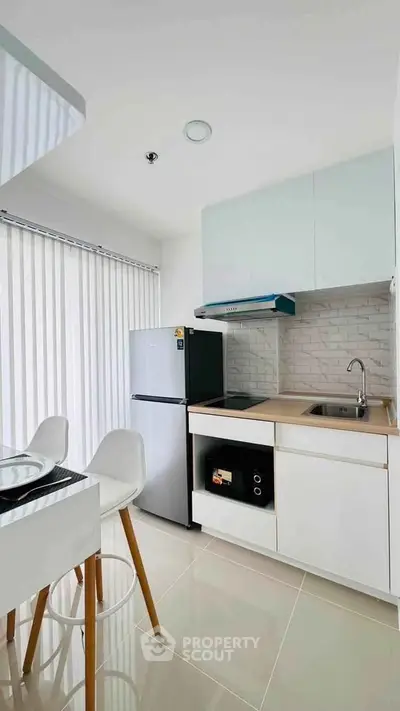 Modern kitchen with sleek white cabinets, built-in appliances, and natural light from large windows.