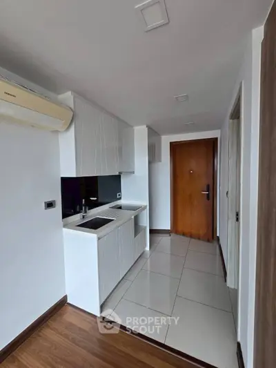 Modern compact kitchen with sleek cabinetry and air conditioning unit.