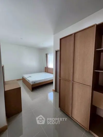 Spacious bedroom with modern wooden furniture and sleek tiled flooring