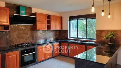 Modern kitchen with wooden cabinets, sleek countertops, and large window offering natural light.