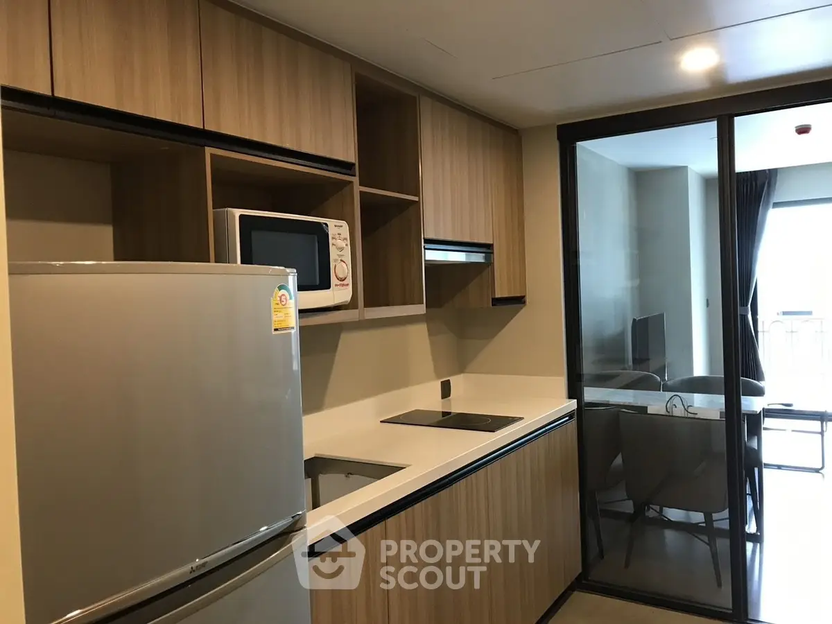 Modern kitchen with sleek appliances and open layout leading to dining area.