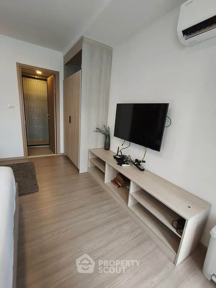 Modern living room with sleek TV setup and air conditioning in a stylish apartment.