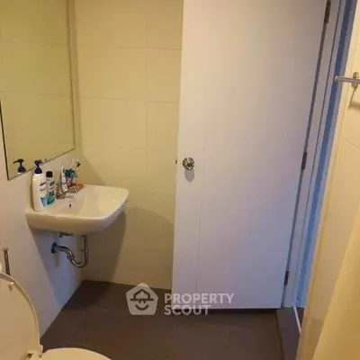 Compact bathroom with wall-mounted sink and mirror, ideal for small spaces.