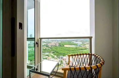 Stunning balcony view with modern chair and table overlooking lush greenery and cityscape.