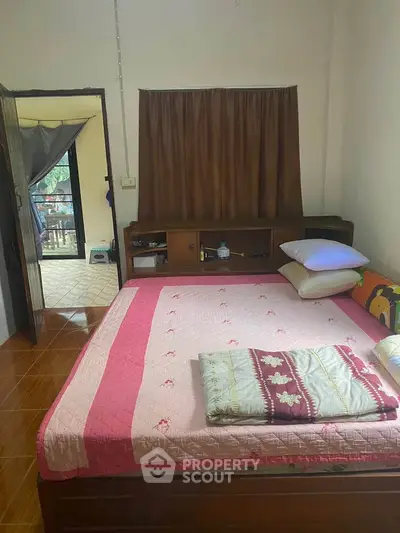 Cozy bedroom with wooden flooring and large bed, offering a warm and inviting atmosphere.