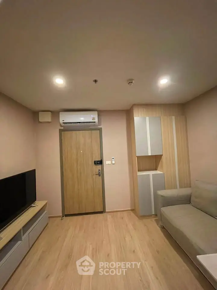 Modern living room with sleek design, featuring a cozy sofa, flat-screen TV, and stylish wooden flooring.