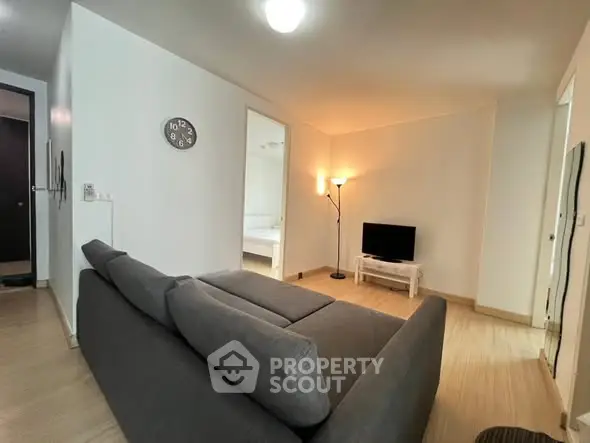 Modern living room with sleek gray sofa and wall-mounted clock, perfect for cozy relaxation.