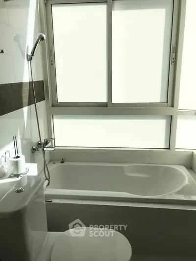 Bright bathroom with bathtub and large frosted window for privacy