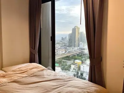 Cozy bedroom with stunning city view from large window, perfect urban retreat.