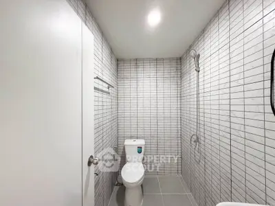 Modern minimalist bathroom with sleek tile design and shower area.