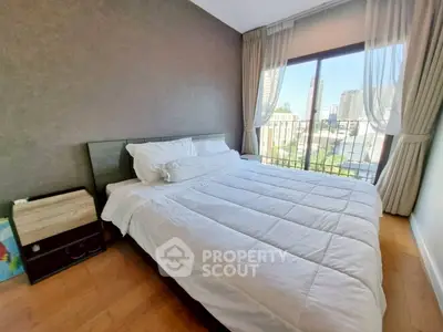 Bright and cozy bedroom with large window offering city views, perfect for relaxation.