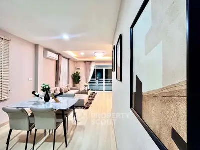 Modern living room with elegant dining area and stylish decor, featuring large windows and contemporary furniture.