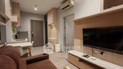 Modern living room with cozy sofa, wall-mounted TV, and stylish wooden cabinetry.
