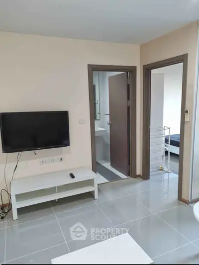 Modern apartment interior with TV, open doors to bathroom and bedroom, sleek tiled flooring.
