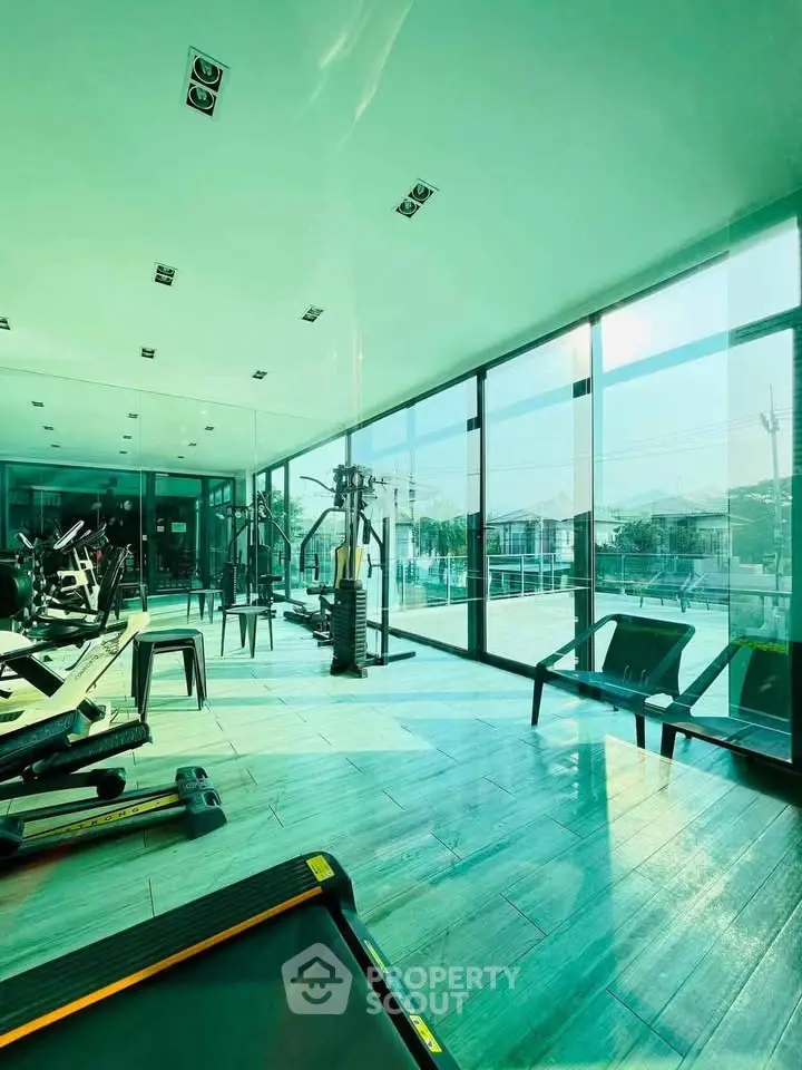 Spacious modern gym with large windows and state-of-the-art equipment, offering a bright and inviting workout space.