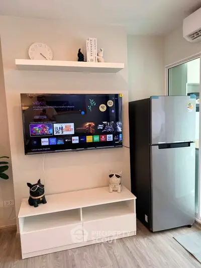 Modern living room with wall-mounted TV and sleek refrigerator, stylish decor and wooden flooring.