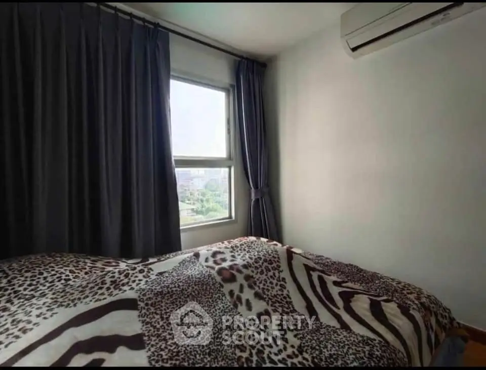 Cozy bedroom with large window and air conditioning, featuring stylish animal print bedding.