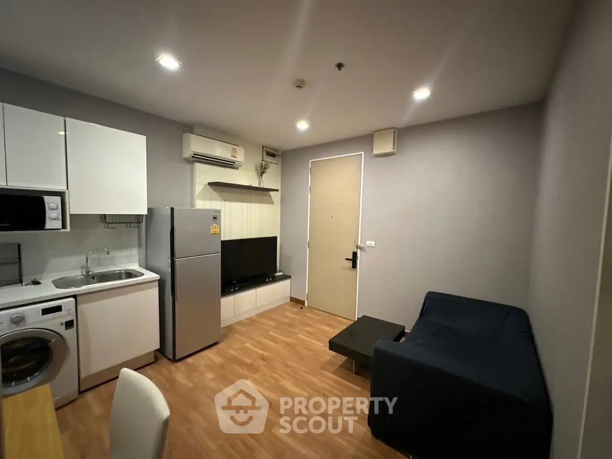 Modern apartment interior with kitchen and living area featuring sleek appliances and cozy seating.