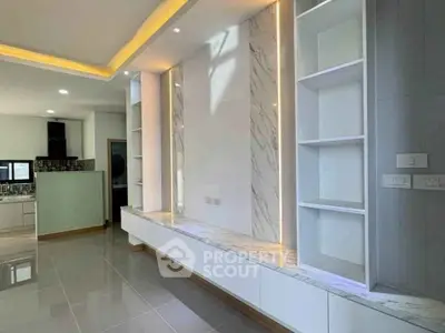 Modern living room with built-in shelves and elegant lighting, featuring a sleek marble accent wall.
