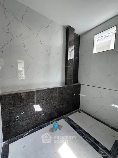 Modern bathroom under construction with marble tiles and natural light