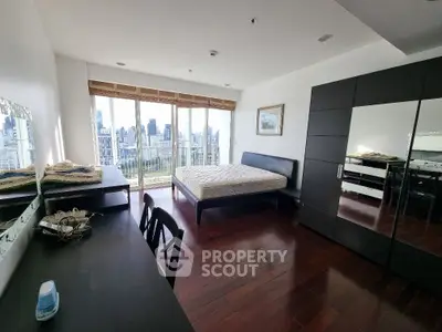 Spacious bedroom with city view, featuring hardwood floors and modern furniture.