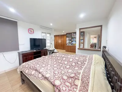 Spacious bedroom with elegant decor and large TV in a cozy home setting.