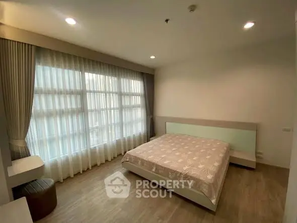 Spacious bedroom with large window and modern decor