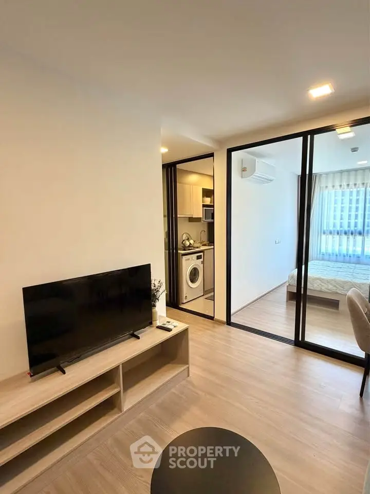 Modern apartment interior with open living room and kitchen, featuring sleek design and natural light.