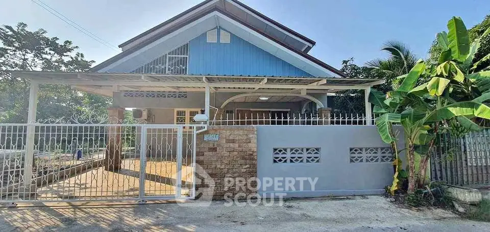 Charming single-story house with gated entrance and lush greenery