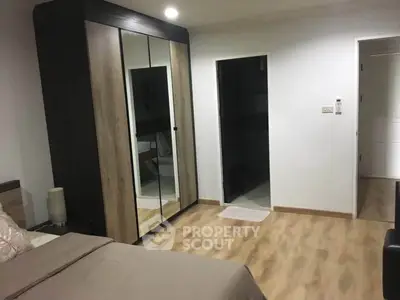 Modern bedroom with mirrored wardrobe and wooden flooring