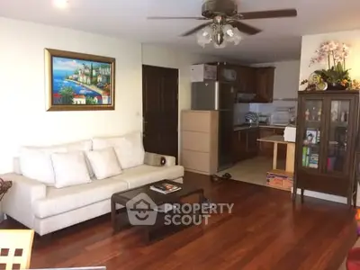Charming living room with hardwood floors, cozy sofa, and open kitchen layout in a modern apartment.