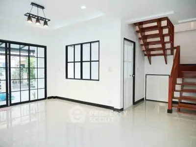 Modern open-plan living room with staircase and large windows