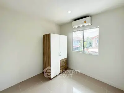 Minimalist bedroom with air conditioning and wardrobe, featuring a bright window view.